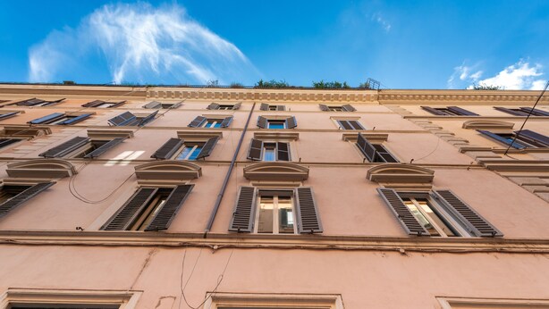 A building with multiple windows and balconies, featuring a classic architectural style with a flat roof and symmetrical design. - Piazza del Popolo Brunetti apartment (Roma)