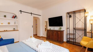 A hotel room with a bed, a wardrobe, a TV, a shelf with books, and a chair. - Piazza del Popolo Brunetti apartment (Roma)