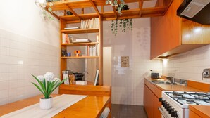 A kitchen with a wooden table, a gas stove, and a bookshelf. - Piazza del Popolo Brunetti apartment (Roma)