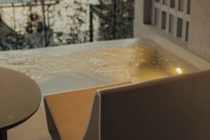 Blick auf eine Terrasse mit Tisch und Stühlen, ein Gebäude im Hintergrund und eine Lichtquelle am Boden.