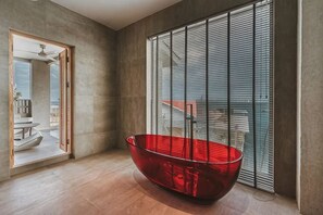 Ein modernes Interieur mit einer roten Badewanne, großen Fenstern und Blick ins Freie.