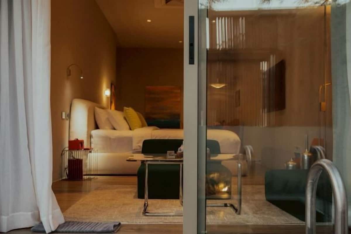 Une chambre d’hôtel moderne avec un canapé, une table basse et une cloison en verre.