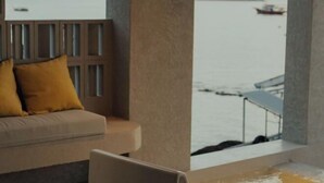 Habitación con vista a un cuerpo de agua, un sofá con cojines y una silla.