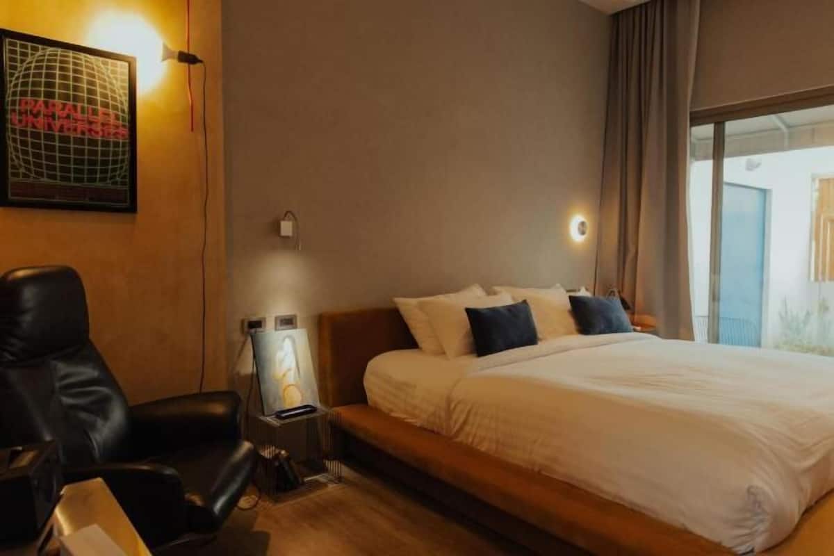 Une chambre d’hôtel équipée d’un lit, d’un bureau, d’une chaise, d’une lampe et d’un globe terrestre fixé au mur.