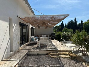 Une terrasse avec des meubles d’extérieur, une pergola et un espace jardin agrémenté de plantes et d’une petite piscine.