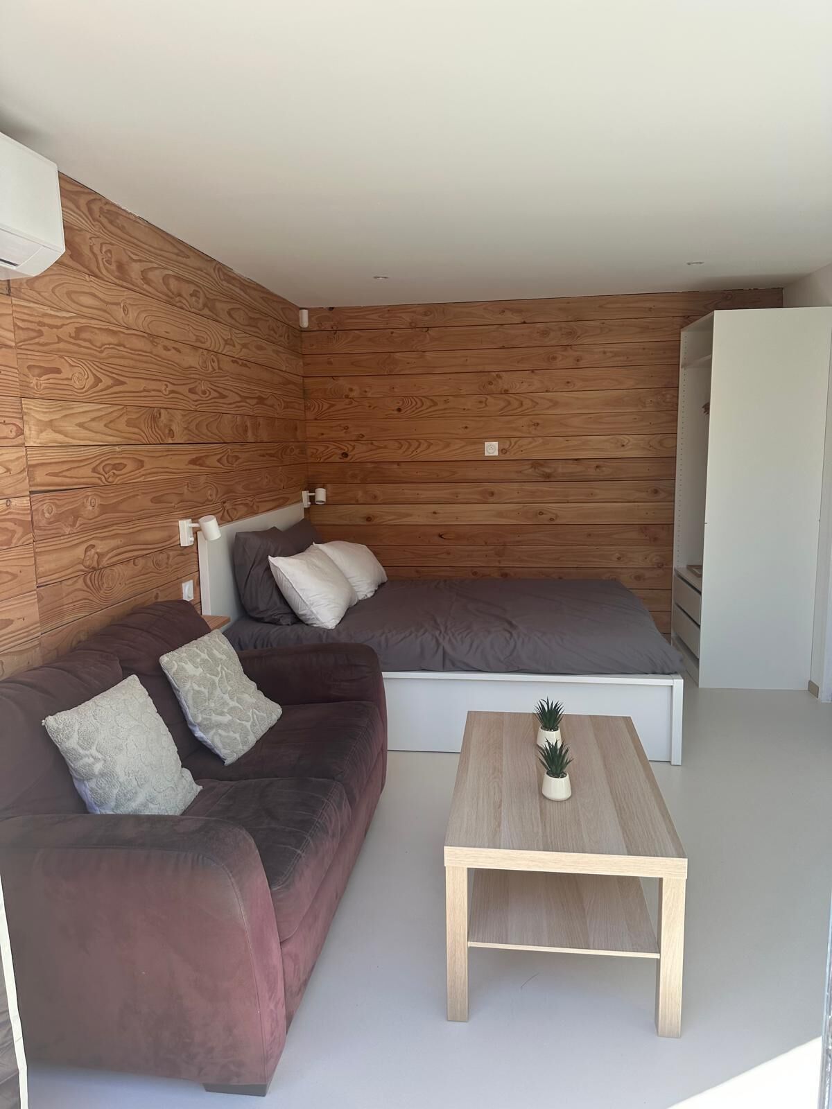 Un salon moderne avec un mur en bois, un canapé, un lit et une table basse.