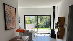 A modern interior with a wooden table, a framed artwork, and a view of a covered outdoor area.