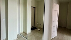 Ein Zimmer mit einer Schiebetür zu einem Badezimmer, einem weißen Kleiderschrank und einem hellen Holzboden.
