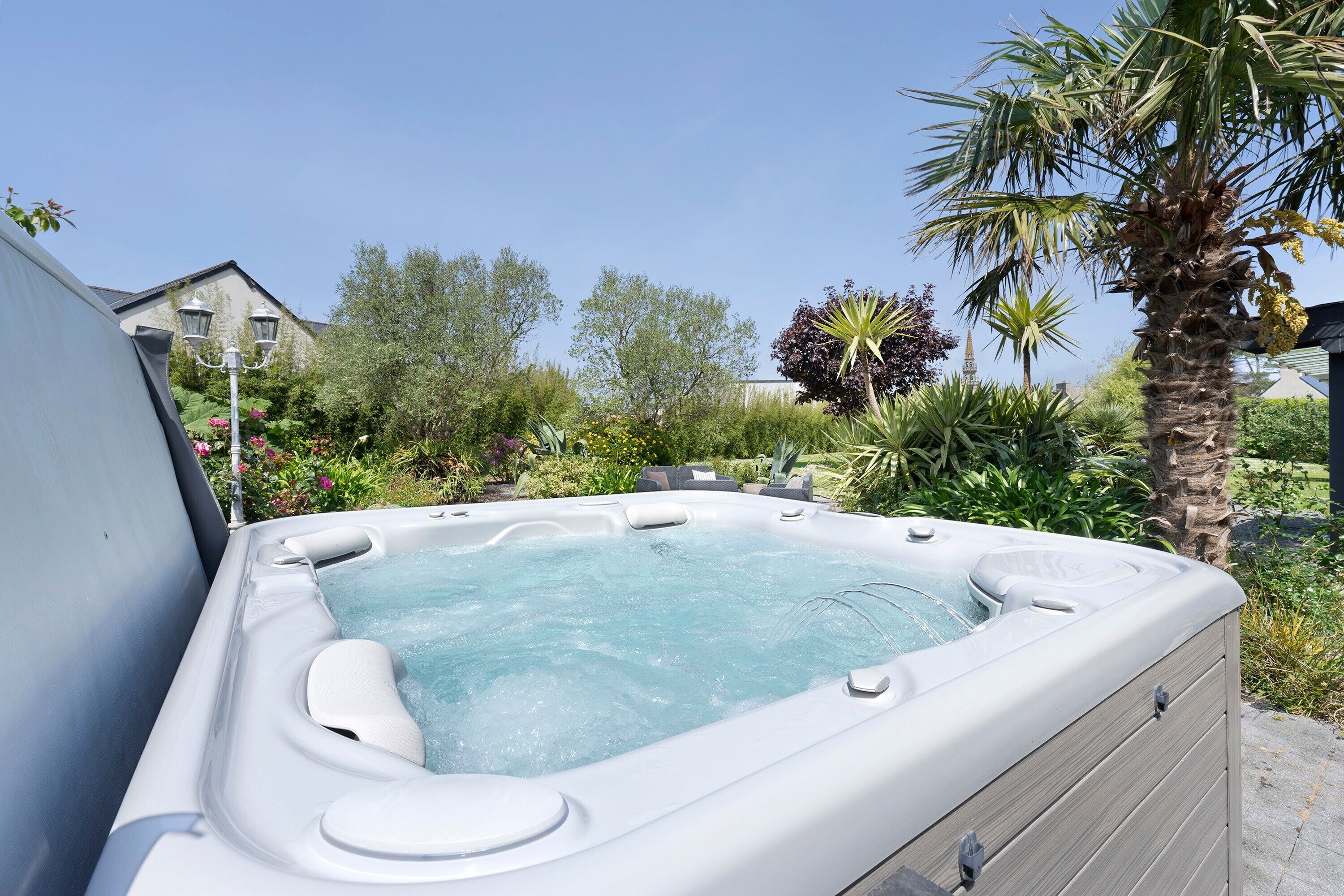 Un bain à remous dans un jardin, avec une maison en arrière-plan.