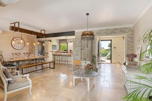 A spacious living area with a dining table, chairs, a round coffee table, and a hanging light fixture.