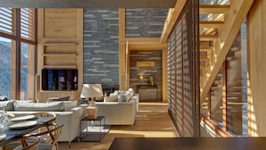 A modern interior with a wooden floor, a sofa, a dining table, and a fireplace.