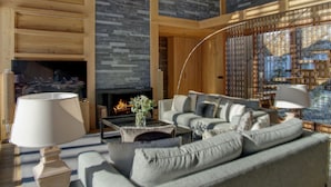 A modern living room with a fireplace, a sofa set, and a large window with a view.