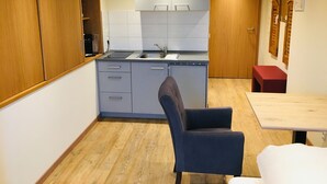 Une cuisine compacte avec des meubles en bois, un évier encastré et un coin repas comprenant une table et une chaise.