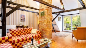 Ein gemütliches Wohnzimmer mit einem karierten Sofa, einem Kamin und Blick ins Freie.