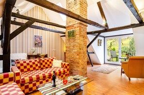 Un salon chaleureux avec un canapé à carreaux, une cheminée et une vue sur l’extérieur.