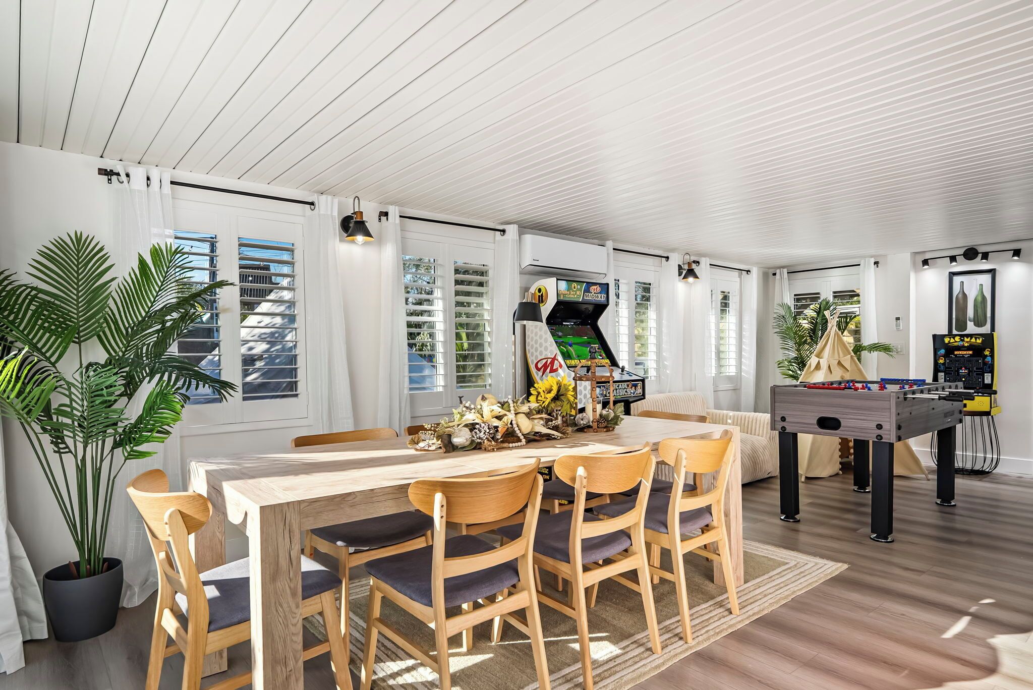 Ein Essbereich mit einem Holztisch und Stühlen, einem Kicker und einer großen Pflanze.