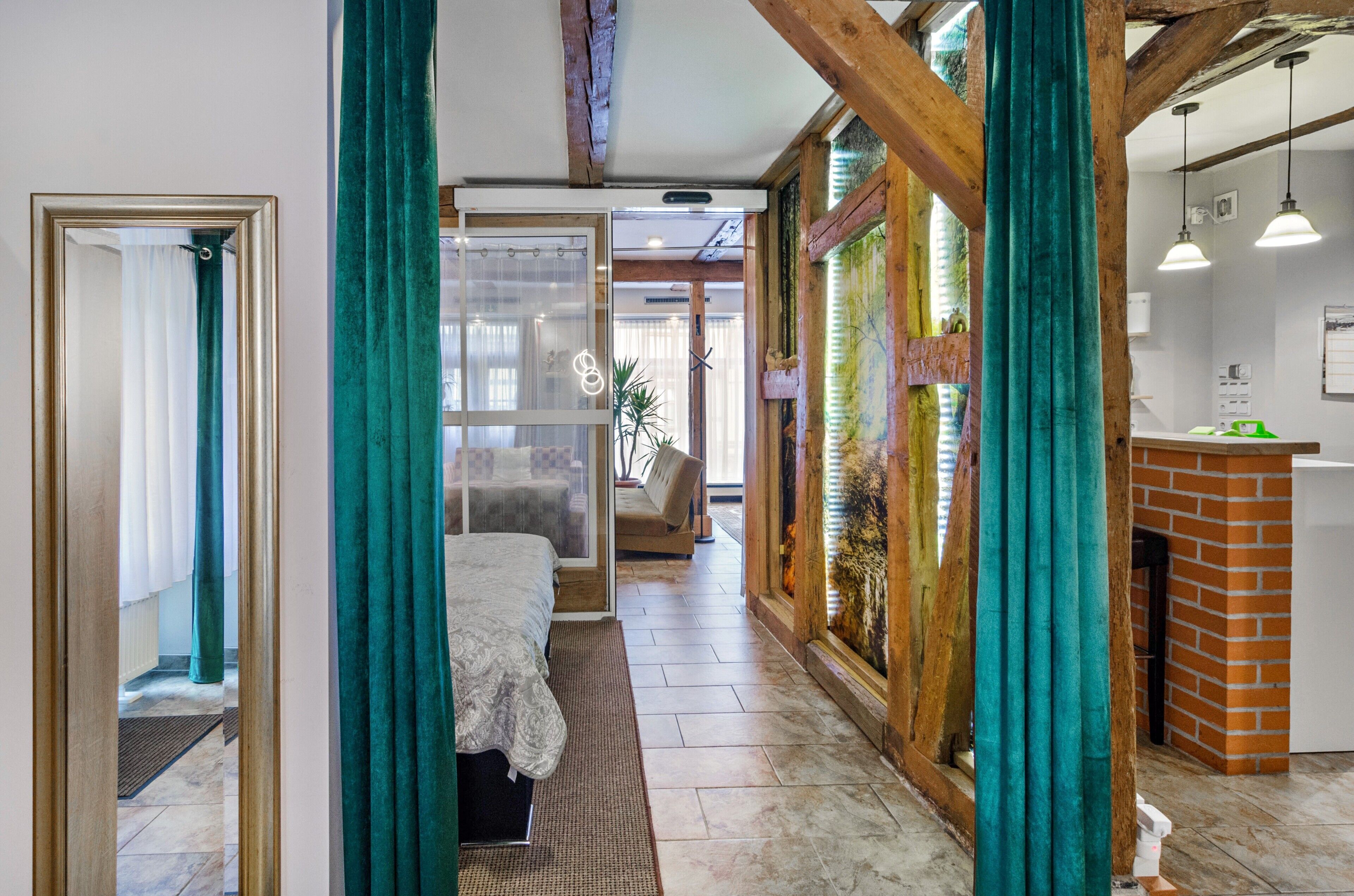Une chambre d’hôtel comprenant un lit, un petit coin salon, une cheminée et un coin cuisine.