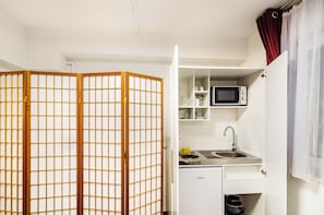 A compact kitchen with a microwave, sink, and storage cabinets.