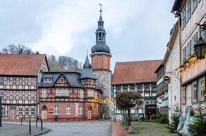 A historic town square with traditional half-timbered buildings, a prominent tower, and cobblestone streets.