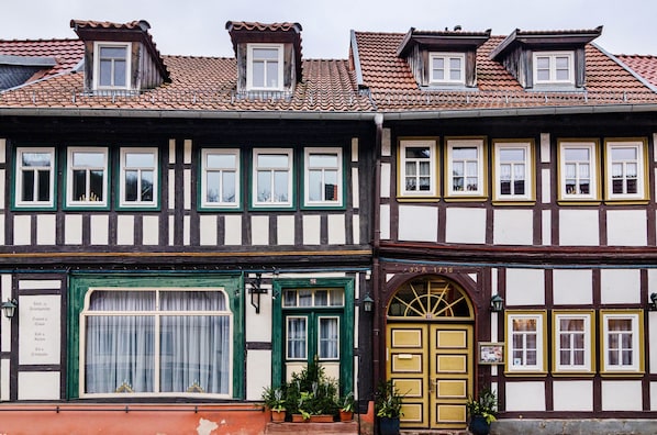 A traditional half-timbered building with multiple windows, a green door, and a yellow door.