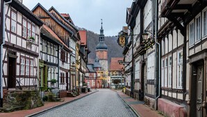 A cobblestone street lined with traditional half-timbered buildings, a church with a dome, and a hotel sign. - Apartment "Double Room with Private Bathroom" (Stolberg i. Harz)