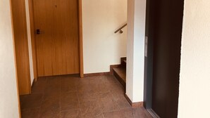A hallway with a wooden door, a staircase, and a dark door at the end. - Apartment '6' with Shared Terrace and Wi-Fi (Mössingen)