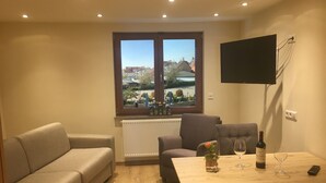 A living room with a sofa, armchair, and a table with wine glasses and a bottle. - Apartment '6' with Shared Terrace and Wi-Fi (Mössingen)