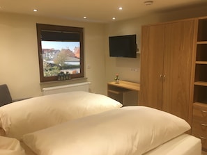 A bedroom with two beds, a window with a view, a TV, and a wooden wardrobe. - Apartment '6' with Shared Terrace and Wi-Fi (Mössingen)