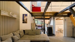 Un interior moderno con un sofá modular, una silla roja y una cocina visible a través de una puerta abierta.