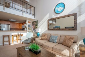 A modern living room with a sofa, coffee table, and a large mirror.