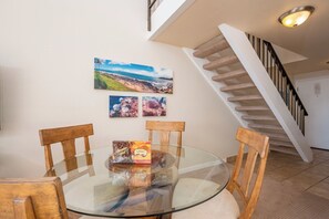 Spiseområde med et glasbord, træstole og en kasse med hawaiiansk tema.