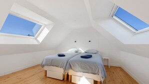 A bedroom with two beds, wooden flooring, skylights, and a white ceiling. - Ty Bidou, charming house near the sea (Kerlouan)