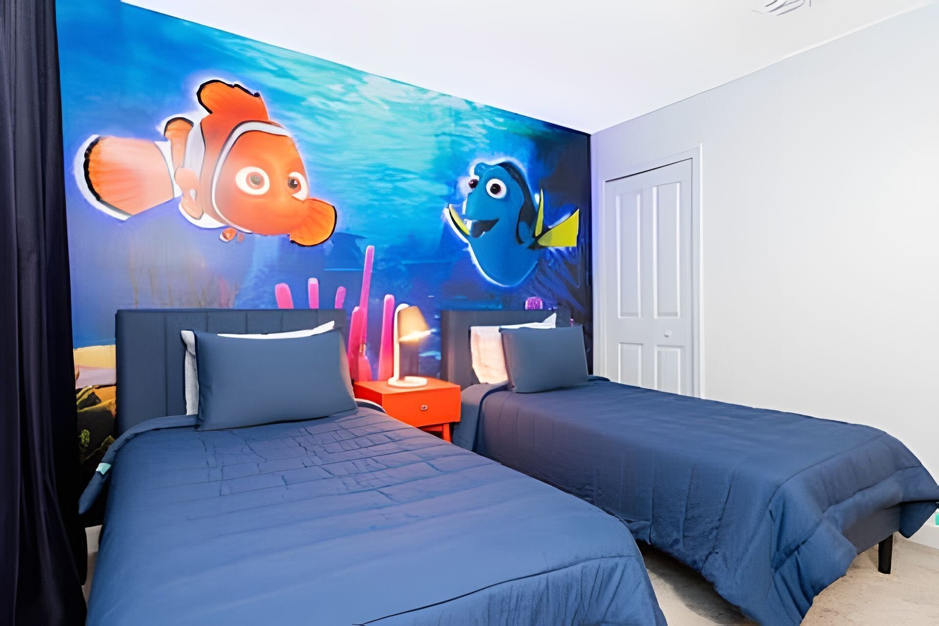 A hotel room with two beds, a mural of fish, and a door.