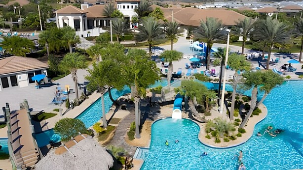 Un resort con una piscina grande, palmeras y una cabaña de techo de paja.