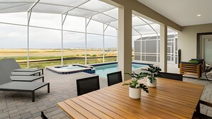 Un espacio al aire libre techado con piscina, mobiliario y vistas al paisaje.