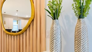 Un interior moderno con un espejo grande, dos jarrones decorativos y un revestimiento de pared de madera.