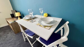 Una mesa de comedor con platos blancos, dos copas de vino y un candelabro amarillo.