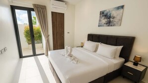 Un dormitorio con una cama grande, una mesita de noche, una lámpara de pared, un ventanal corredizo y un cuadro en la pared.
