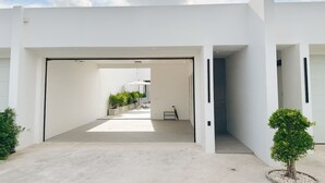 Un edificio moderno con un espacio central abierto, una zona de estar cubierta y plantas en macetas.