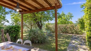 A covered patio with a table, chairs, and a stone pathway.
