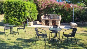 Un patio al aire libre con una barbacoa de piedra y cuatro sillas.