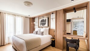A hotel room with a large bed, a desk, a chair, and a mirror. - Merveil Signature Suite - Bateliere (Paris)