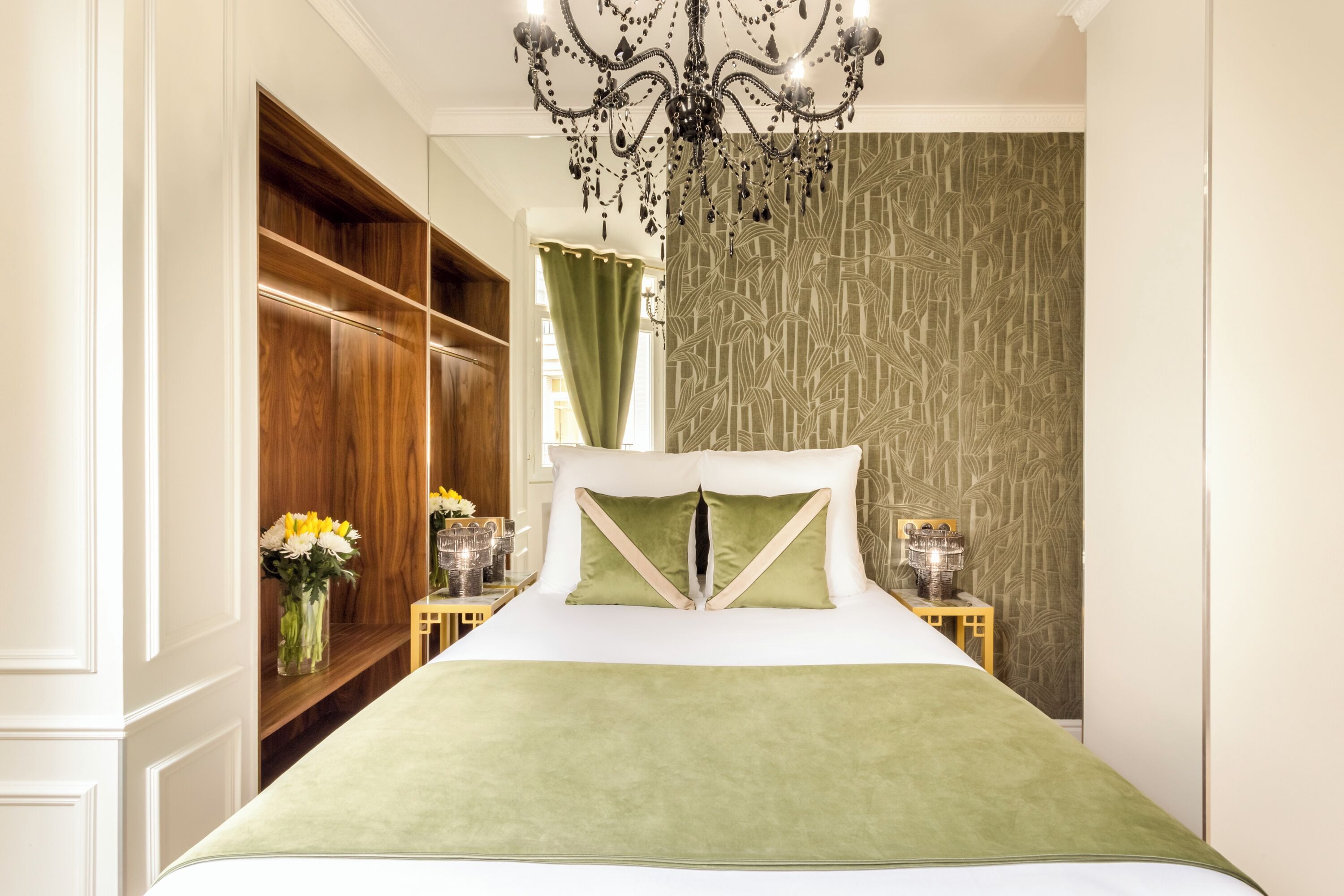 A bedroom with a large bed, wooden wardrobe, and a chandelier.