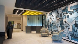 A lobby with a modern design, featuring a large mural, a reception desk, and a unique patterned chair.