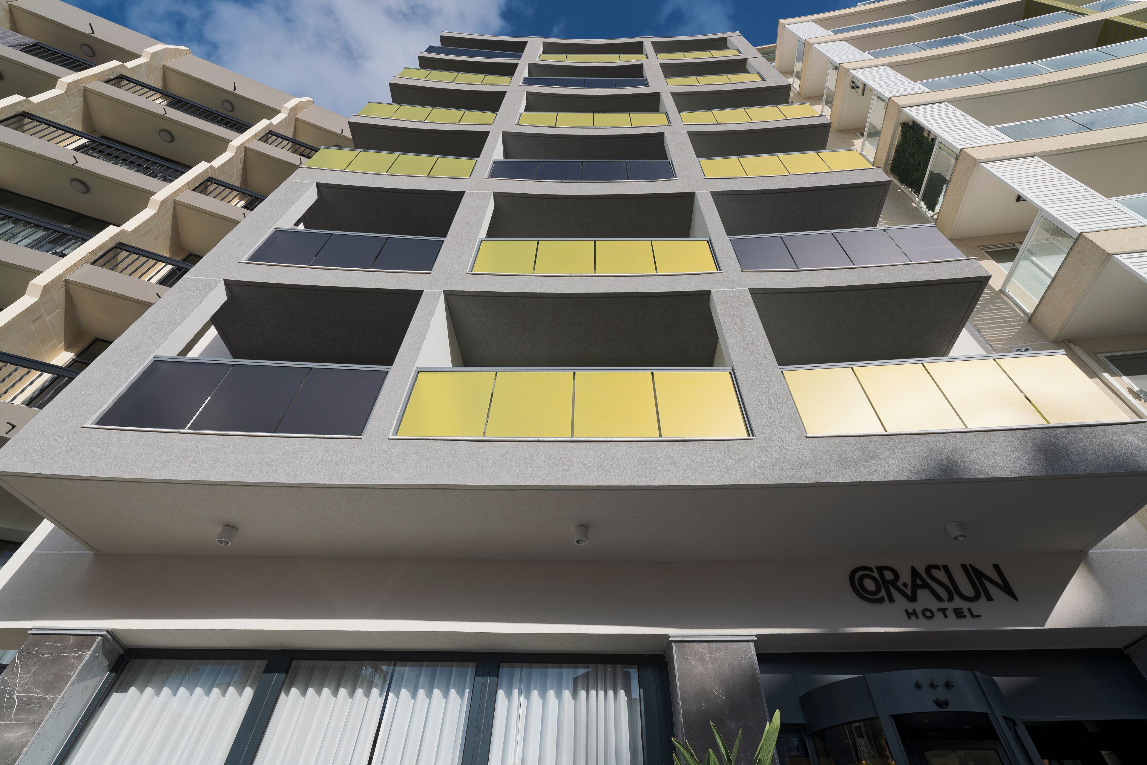 Un moderno edificio alberghiero con diversi balconi e un cielo sereno.
