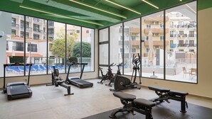 A gym with exercise equipment, large windows, and a view of buildings.