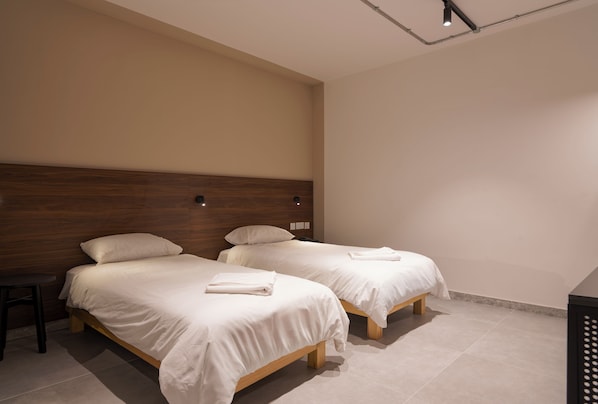 A hotel room with two single beds, a wooden headboard, and a small table. - Cora Sun Hotel (St. Paul's Bay)
