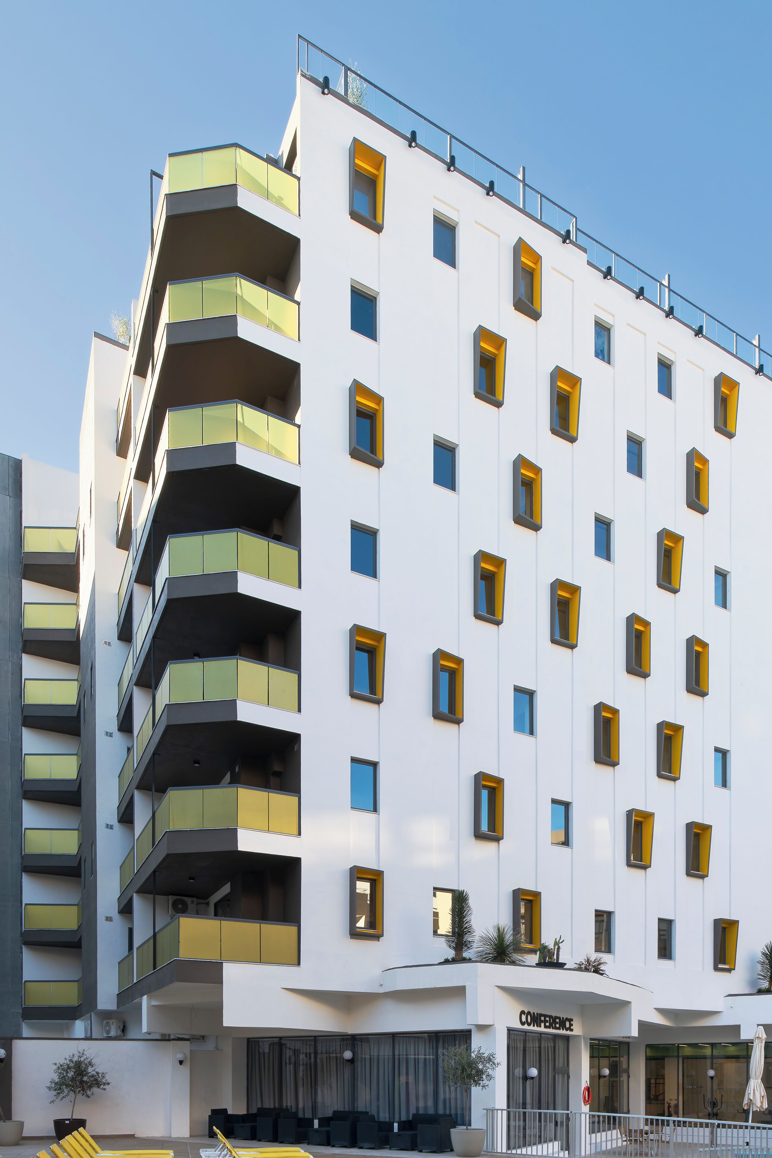 A modern hotel with multiple balconies, a conference center, and a well-maintained outdoor area.