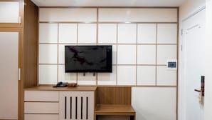 A modern room with a wooden cabinet, a small table, and a mounted TV on a tiled wall.