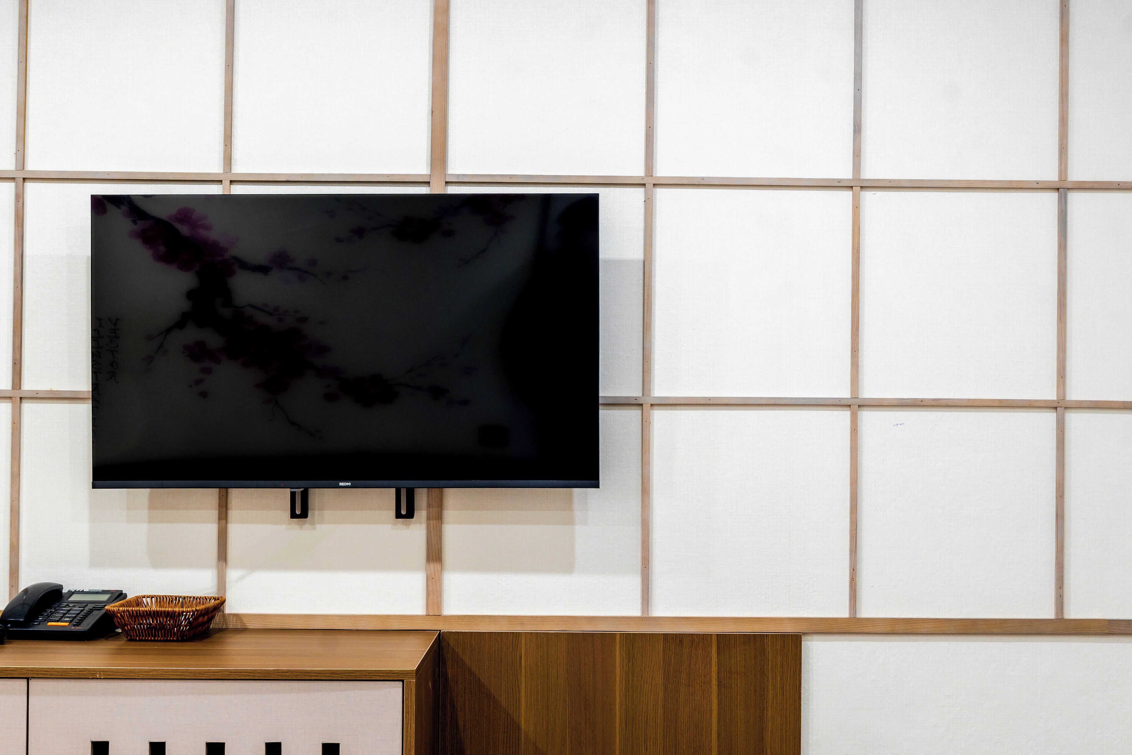 A flat-screen TV mounted on a wall with a grid pattern.